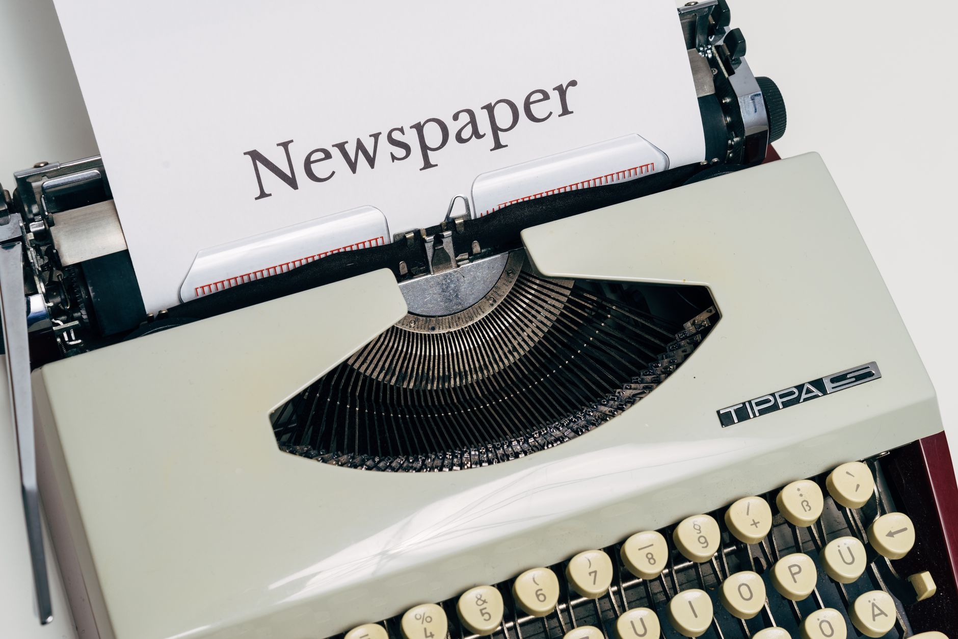 Early 20th-century journalist writing on a typewriter, symbolizing the pre-digital era of news.