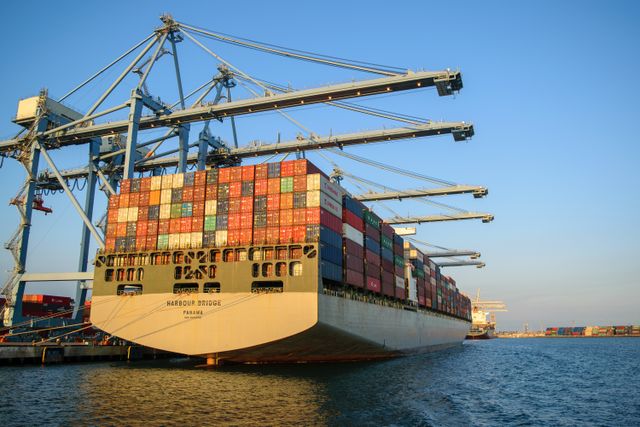 Containers being loaded onto a cargo ship in a busy port, symbolizing international trade.