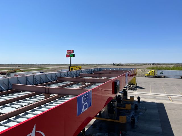 Una bomba de diésel en una gasolinera de Estados Unidos mostrando un precio alto por galón, con un camión de transporte al fondo.