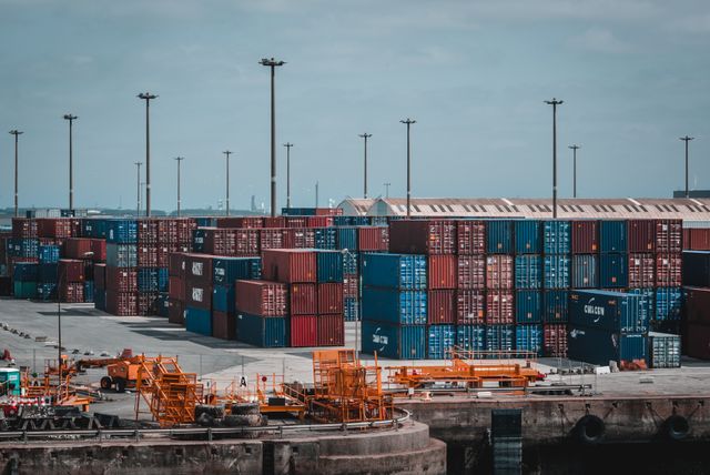 Contenedores de carga y barcos en un puerto global que simbolizan el comercio internacional y la economía.