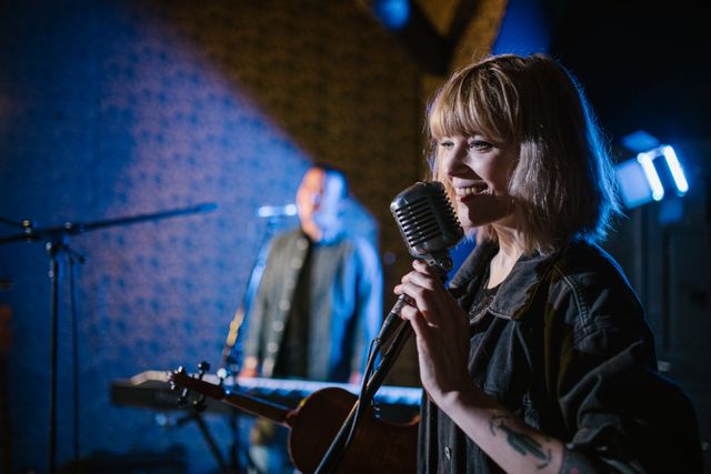 Carola Häggkvist cantando con pasión en el escenario, bajo luces de colores, con una pose dinámica.