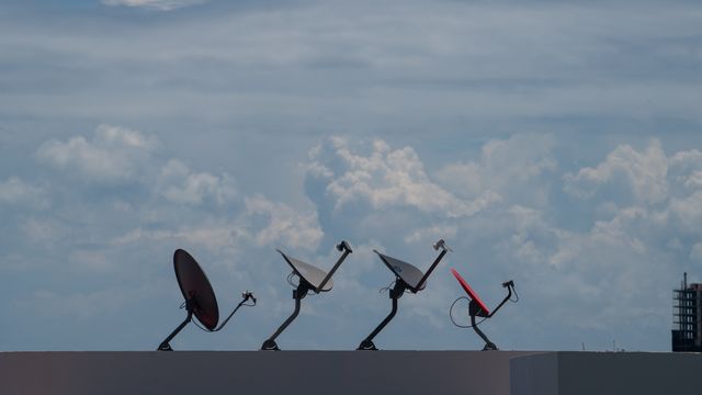 Una antena parabólica pequeña de las primeras de SKY México, instalada en el techo de una casa con el horizonte de la Ciudad de México de fondo.