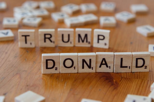 Donald Trump hablando desde un podio con un fondo que insinúa gráficos económicos o un mapa mundial.