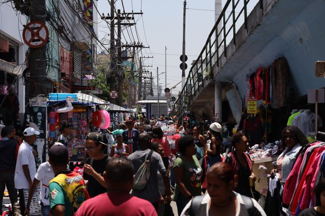 Un mercado al aire libre lleno de vida en una ciudad colombiana, con vendedores y compradores interactuando entre productos frescos y artesanías.