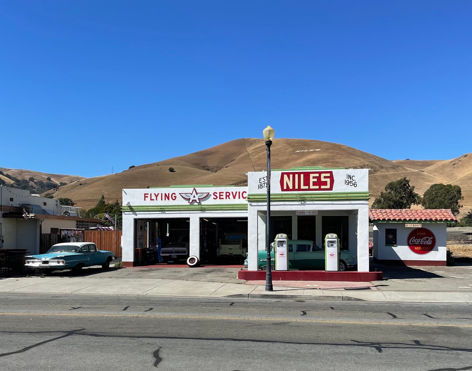 A classic car parked on a scenic California road with a landscape in the background.
