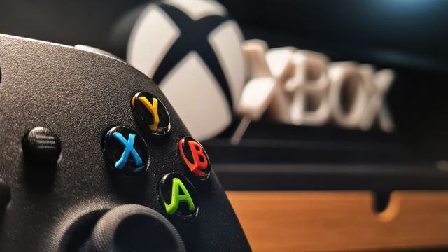 Un control de Xbox Series X descansando sobre una superficie oscura en un entorno de oficina moderno.