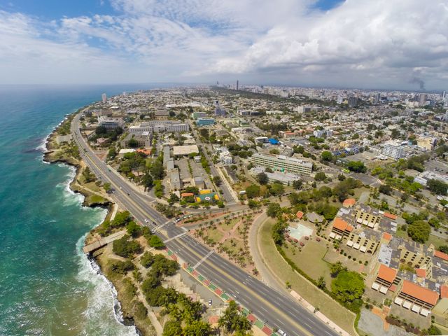 Vista aérea de Santo Domingo al anochecer, con edificios iluminados y autopistas con tráfico, simbolizando la conectividad digital y el desarrollo urbano.