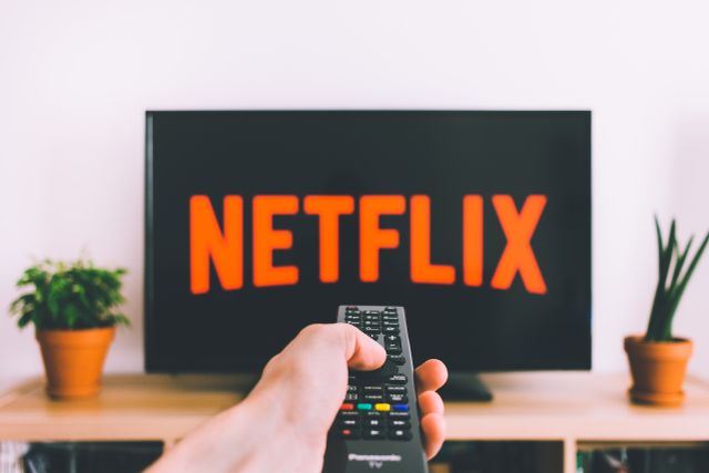 Una persona viendo contenido de Netflix en una pantalla de televisión en un salón moderno.