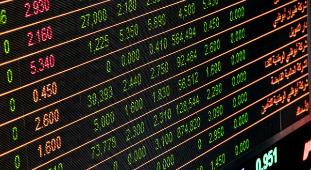 Traders on the New York Stock Exchange floor reviewing financial data on screens.