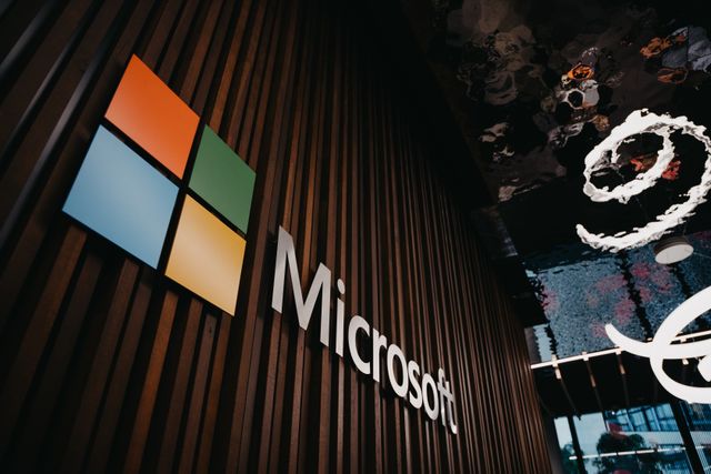 Una persona jugando Microsoft Jewel en un smartphone, mientras un portátil en el fondo muestra el mismo juego.